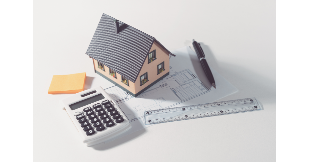 Model house on blueprints with calculator, ruler, and pen, symbolizing home price negotiation strategies in Calgary real estate.